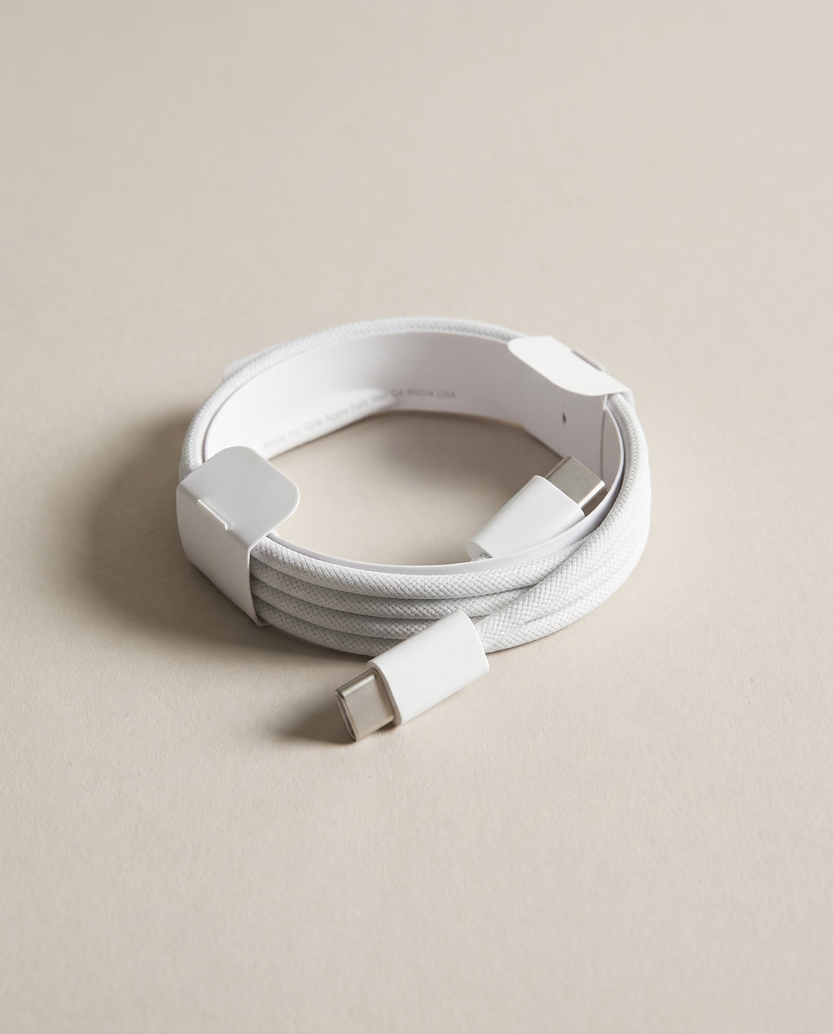 Cable USB-C de Apple enrollado con su precinto de papel, tal y como viene en la caja